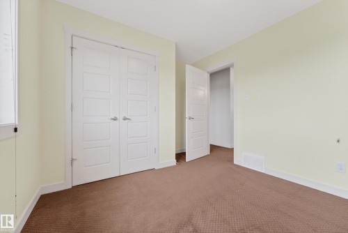 Neutral-toned room featuring a patterned brown carpet and light cream walls - 5244 1A Avenue, Edmonton, AB 