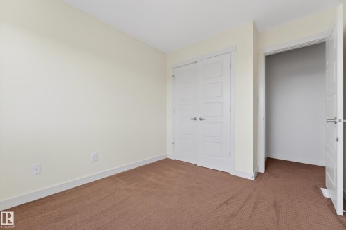 Carpeted interior room featuring neutral wall tones, white baseboards, and two white panel doors - 5244 1A Avenue, Edmonton, AB 