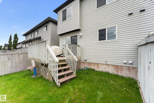 Rear exterior featuring siding, an elevated wood deck with lattice skirting, and a sliding glass door - 5244 1A Avenue, Edmonton, AB 