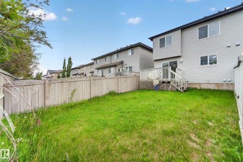 Expansive backyard featuring a wood privacy fence, a multi-level wood deck, and a sliding glass patio door - 5244 1A Avenue, Edmonton, AB 