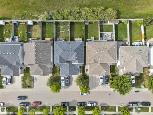 Residential street featuring a row of properties with asphalt shingle roofs, paved driveways, and green lawns - 5244 1A Avenue, Edmonton, AB 