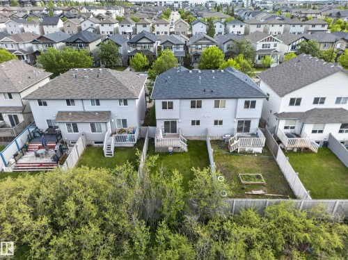 Rear exterior featuring a grey shingle roof, light-colored siding, and multiple windows - 5244 1A Avenue, Edmonton, AB 