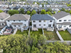 Rear exterior featuring a grey shingle roof, light-colored siding, and multiple windows - 