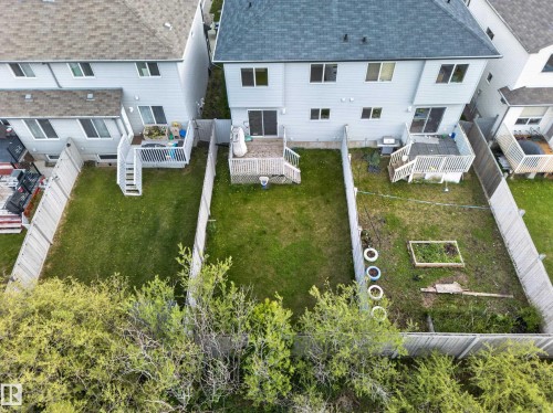 Private fenced backyard with a wooden deck, sliding glass door access, and an established garden bed - 5244 1A Avenue, Edmonton, AB 