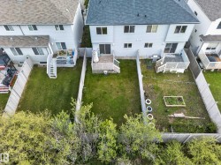 Private fenced backyard with a wooden deck, sliding glass door access, and an established garden bed - 