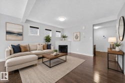 Spacious living area featuring rich wood-finish flooring, a tiled fireplace with a white mantel, and recessed lighting - 