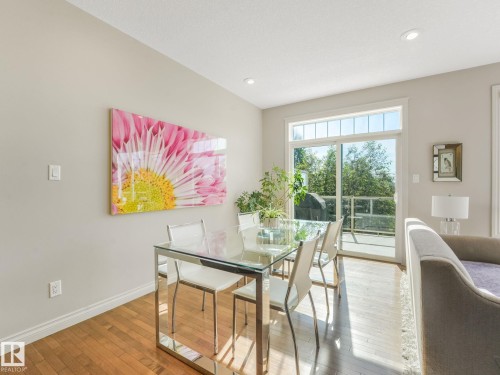 Dining area featuring wood-finish flooring, recessed lighting, and a glass sliding door with transom window providing direct exterior access - 3 1641 James Mowatt Trail, Edmonton, AB 