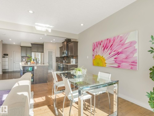 Kitchen featuring dark wood cabinetry, stainless steel appliances, and a central island with a breakfast bar - 3 1641 James Mowatt Trail, Edmonton, AB 