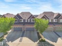Townhouse exteriors featuring stone accents, gabled roofs, attached garages, paved driveways, and mature trees - 3 1641 James Mowatt Trail, Edmonton, AB 