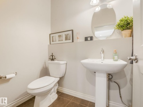 Pedestal sink with chrome faucet, oval mirror, and three-bulb vanity lighting - 3 1641 James Mowatt Trail, Edmonton, AB 