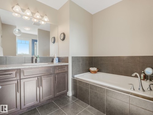 Soaking tub with chrome fixtures, surrounded by dark gray tile - 3 1641 James Mowatt Trail, Edmonton, AB 