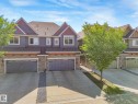 Contemporary townhome exterior featuring an attached garage, paved driveway, stone accents, and a shingled roof - 3 1641 James Mowatt Trail, Edmonton, AB 
