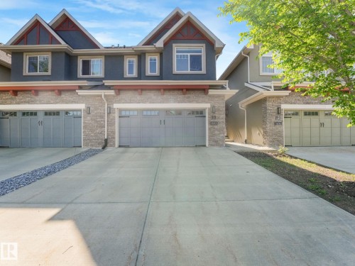 Contemporary exterior featuring multi-toned stucco, stone veneer accents, and gabled rooflines - 3 1641 James Mowatt Trail, Edmonton, AB 