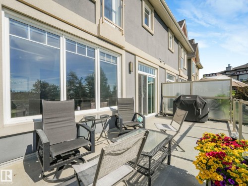 Spacious outdoor main level deck area featuring a ravine view, privacy screening, and glass railing - 3 1641 James Mowatt Trail, Edmonton, AB 
