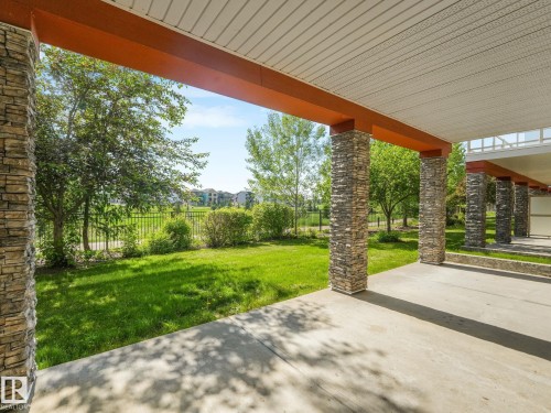 Covered patio space featuring stone-clad pillars, a light-colored soffit ceiling, and concrete flooring - 3 1641 James Mowatt Trail, Edmonton, AB 