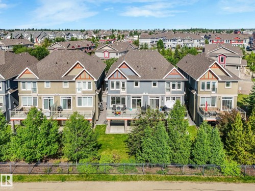 Rear exteriors of three multi-story properties featuring individual decks, sliding glass doors, and ground-level patios - 3 1641 James Mowatt Trail, Edmonton, AB 