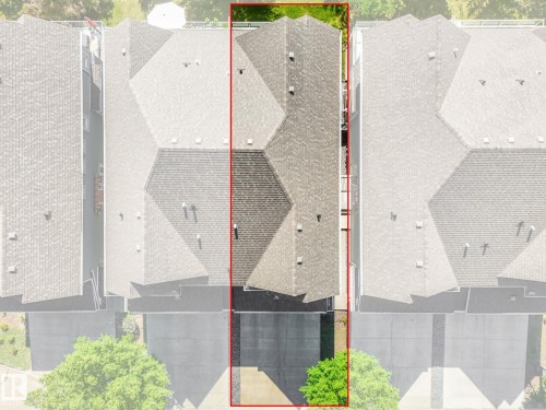 Townhome property featuring a multi-pitched shingle roof, asphalt driveway, and a small green space at the front - 3 1641 James Mowatt Trail, Edmonton, AB 