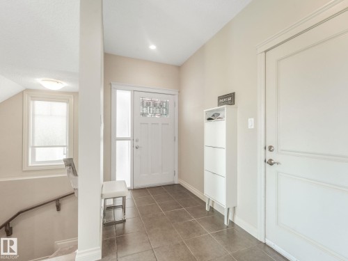 Front entryway with tiled flooring, white paneled door, and a decorative glass insert - 3 1641 James Mowatt Trail, Edmonton, AB 