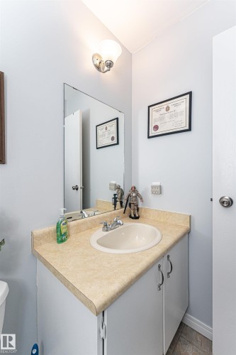 Bathroom vanity featuring a laminate countertop, integrated sink, and white cabinetry with curved hardware - 18 Walden Park, St. Albert, AB 