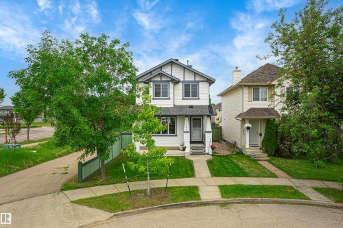 Two-story residence featuring white siding with dark trim accents, a front porch, and mature landscaping - 21384 88 Avenue, Edmonton, AB 