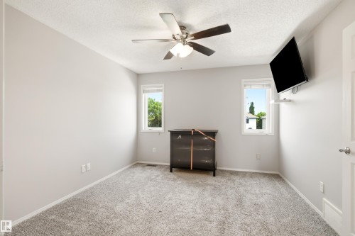Room featuring light gray wall paint, gray carpet flooring, a ceiling fan with integrated lighting, and two windows allowing natural light - 21384 88 Avenue, Edmonton, AB 