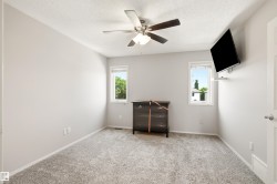 Room featuring light gray wall paint, gray carpet flooring, a ceiling fan with integrated lighting, and two windows allowing natural light - 