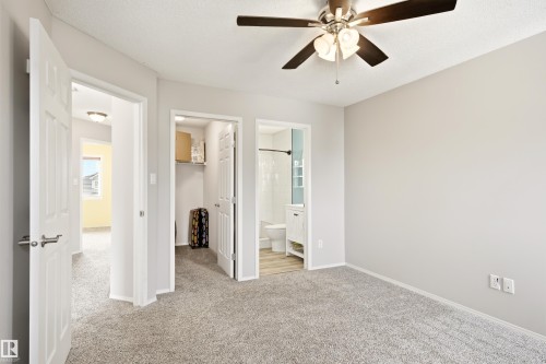Light gray carpeted room featuring a ceiling fan with light fixture, white trim, and a three-panel interior door - 21384 88 Avenue, Edmonton, AB 
