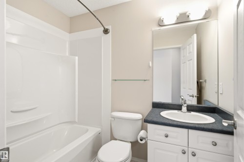 Full bathroom featuring a white tub/shower combination, white toilet, and a vanity with a dark countertop and white cabinetry - 21384 88 Avenue, Edmonton, AB 