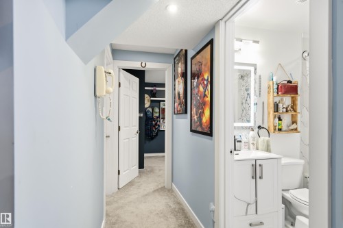 Compact bathroom featuring a white vanity with under-sink storage, a modern illuminated mirror, and a wall-mounted wooden shelving unit - 21384 88 Avenue, Edmonton, AB 