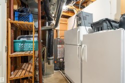 Basement utility area featuring two freestanding refrigerators, exposed ceiling joists, and a hot water heater - 