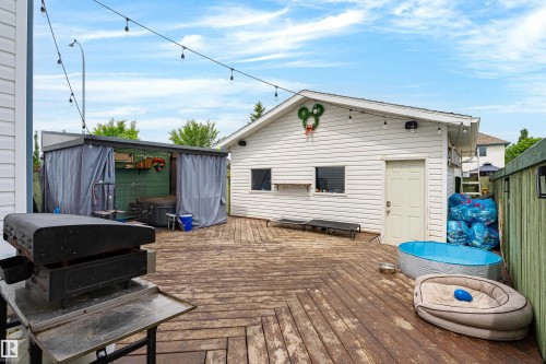 Expansive wooden deck featuring string lighting and a white detached building with side entry - 21384 88 Avenue, Edmonton, AB 