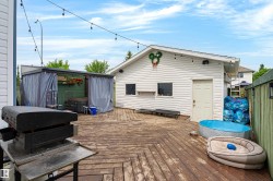 Expansive wooden deck featuring string lighting and a white detached building with side entry - 