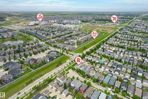 Aerial perspective showcasing a residential development with varied housing styles, surrounding green spaces, and a visible pond feature - 21384 88 Avenue, Edmonton, AB 