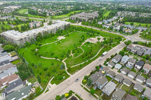Expansive green space featuring walking paths and mature trees, bordered by multi-story residential buildings and detached single-family homes - 21384 88 Avenue, Edmonton, AB 