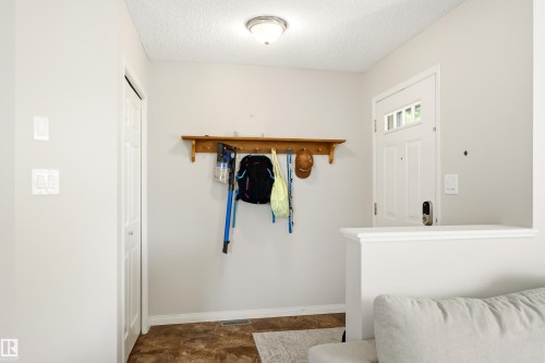 Entryway featuring a white paneled door with glass inserts, wood-finish flooring, and a built-in wooden coat rack - 21384 88 Avenue, Edmonton, AB 