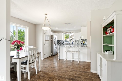 Open-concept dining area with wood-finish flooring, a white trim window, and a contemporary ceiling fixture - 21384 88 Avenue, Edmonton, AB 
