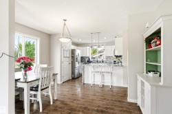 Open-concept dining area with wood-finish flooring, a white trim window, and a contemporary ceiling fixture - 