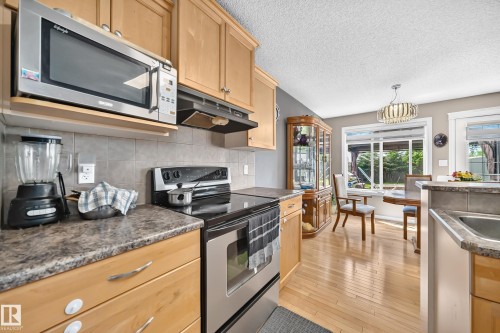 Kitchen featuring light wood cabinetry, stainless steel appliances, patterned laminate countertops, and a tile backsplash - 3224 26 Street, Edmonton, AB 