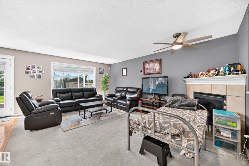 Living area featuring a ceiling fan, fireplace with tile surround, and large window - 3224 26 Street, Edmonton, AB 