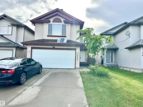 Two-story residential building with light-colored siding, a two-car garage, and a concrete driveway - 3224 26 Street, Edmonton, AB 