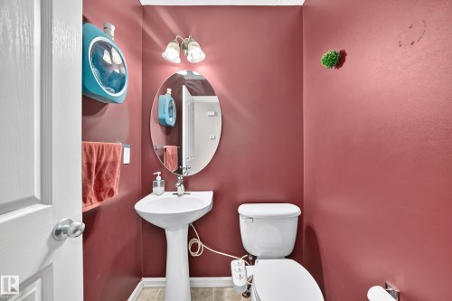 Pedestal sink with an oval frameless mirror, complemented by a two-light vanity fixture - 3224 26 Street, Edmonton, AB 