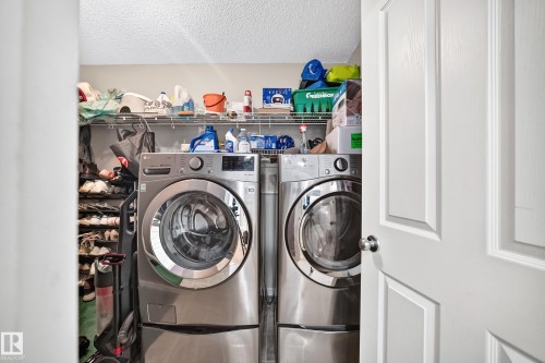 Dedicated laundry area featuring front-loading appliances, upper wire shelving, and textured ceiling - 3224 26 Street, Edmonton, AB 
