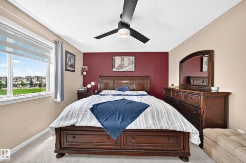 Spacious bedroom featuring neutral wall tones with an accent wall, a large window with roller shades, recessed lighting, and a ceiling fan - 3224 26 Street, Edmonton, AB 