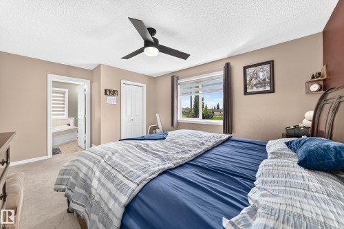 Spacious bedroom featuring neutral wall tones with an accent wall, window with horizontal blinds, ceiling fan, and carpet flooring - 3224 26 Street, Edmonton, AB 