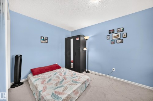 Bedroom featuring light blue walls, a textured ceiling, neutral carpet flooring, and white baseboards - 3224 26 Street, Edmonton, AB 