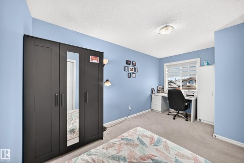 Carpeted room with light blue walls, featuring a window with horizontal blinds, a ceiling-mounted light fixture, and white baseboards - 3224 26 Street, Edmonton, AB 
