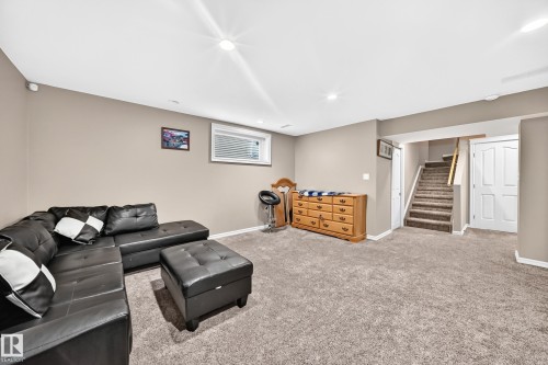Carpeted recreation area with neutral wall tones, recessed lighting, a window, and access to a carpeted staircase - 3224 26 Street, Edmonton, AB 