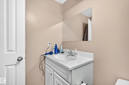 Built-in vanity with a white countertop and integrated sink, chrome faucet, and rectangular wall mirror - 3224 26 Street, Edmonton, AB 