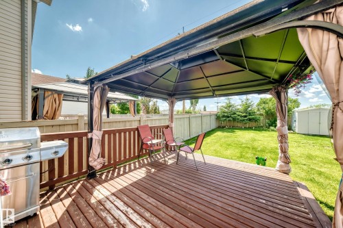 Expansive wood-finish deck featuring a built-in pergola with privacy drapes - 3224 26 Street, Edmonton, AB 