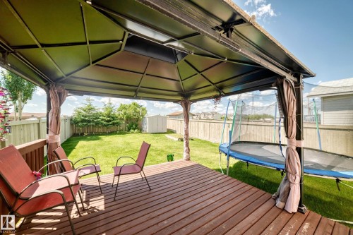 Expansive wood-finish deck featuring a metal-frame gazebo with brown privacy curtains - 3224 26 Street, Edmonton, AB 